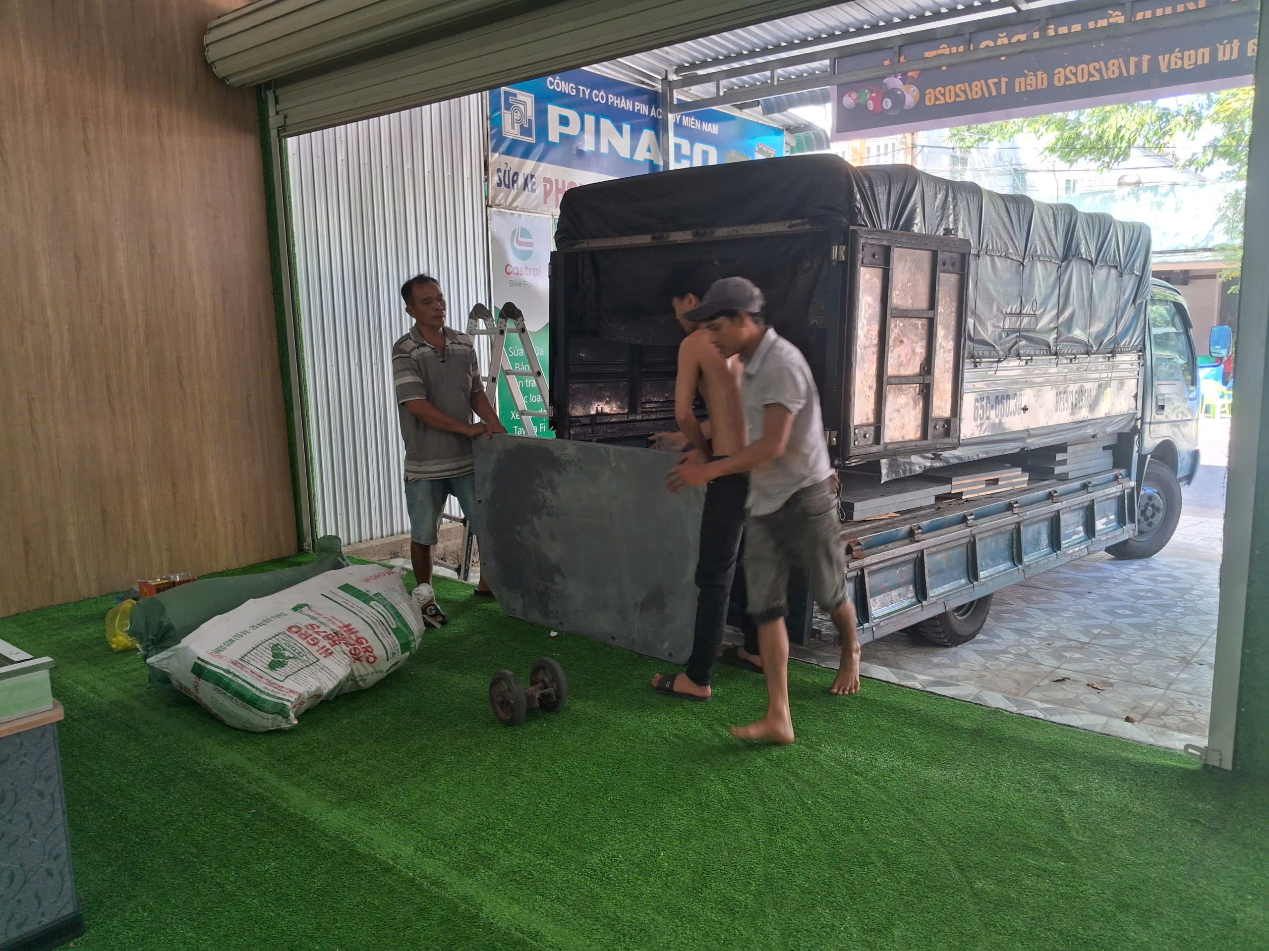 Bàn bida được đưa qua lối vào, minh họa việc chuẩn bị tuyến tiếp cận tại nơi mới.